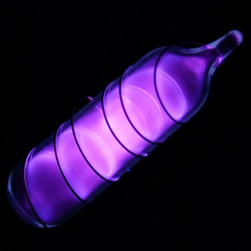 A sealed glass tube of argon gas glowing violet against a black background, with a wire coiled around it